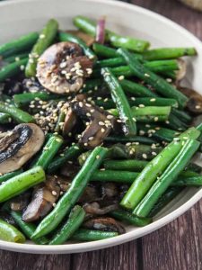 ### Green Bean Mushroom Stir-Fry: A Flavorful, Healthy Dish Green Bean Mushroom Stir-fry is a vibrant, nutrient-packed dish that combines the crisp freshness of green beans with the earthy umami flavor of mushrooms. This simple yet delicious stir-fry is not only quick to prepare but also full of vitamins, antioxidants, and fiber, making it a perfect side dish or even a light main course. With just a few fresh ingredients and a handful of seasonings, you can create a dish that’s both satisfying and healthy. Below is a detailed recipe, including tips for making the most of your ingredients and customizing the flavors to suit your preferences. ### Ingredients: - **2 cups fresh green beans**, trimmed and cut into 1-2 inch pieces - **2 cups mushrooms** (shiitake, button, or cremini mushrooms work best), sliced - **2 tbsp vegetable oil** (or sesame oil for a richer flavor) - **3 cloves garlic**, minced - **1 small onion**, thinly sliced (optional) - **1-inch piece of ginger**, grated or finely minced - **2 tbsp soy sauce** (or tamari for a gluten-free version) - **1 tbsp oyster sauce** (optional, but adds great depth of flavor) - **1 tsp rice vinegar** (for a slight tang) - **1 tsp sesame oil** (for finishing, optional but recommended) - **1 tsp sugar** (to balance the savory flavors) - **1/4 tsp crushed red pepper flakes** (optional, for a touch of heat) - **Sesame seeds** for garnish (optional) - **Fresh cilantro** for garnish (optional) ### Instructions: #### Step 1: Prepare the Ingredients Start by washing and preparing the vegetables. Trim the ends of the green beans and cut them into 1-2 inch pieces. Slice the mushrooms into thin strips or rounds, depending on your preference. Mince the garlic and ginger, and thinly slice the onion (if using). #### Step 2: Blanch the Green Beans (Optional) Blanching the green beans before stir-frying is optional but can help preserve their bright green color and crisp texture. To do this, bring a pot of water to a boil and add the green beans. Let them cook for about 2-3 minutes until they are tender-crisp. Immediately transfer the beans to a bowl of ice water to stop the cooking process. Drain well and set aside. #### Step 3: Stir-fry the Aromatics Heat a large wok or skillet over medium-high heat. Add the vegetable oil and swirl it around to coat the surface. Once the oil is hot, add the minced garlic, ginger, and onion (if using). Stir-fry for about 1-2 minutes until the garlic becomes fragrant and the onions begin to soften. #### Step 4: Add the Mushrooms Add the sliced mushrooms to the pan, stirring constantly to ensure they cook evenly. Mushrooms release a lot of moisture as they cook, so allow them to sauté until most of the liquid has evaporated and they begin to brown, about 5-7 minutes. This is when the mushrooms will develop their deep umami flavor. #### Step 5: Stir-fry the Green Beans If you blanched the green beans, add them to the pan now and stir well to combine with the mushrooms and aromatics. If you didn't blanch them, simply add the raw green beans to the pan and stir-fry for an additional 4-5 minutes until they’re tender-crisp. The green beans should retain a slight bite and vivid color. #### Step 6: Season the Stir-fry Once the vegetables are cooked to your liking, it’s time to add the seasonings. Pour in the soy sauce, oyster sauce (if using), rice vinegar, sesame oil, and sugar. Stir everything together to coat the vegetables in the sauce, and let it cook for another minute to allow the flavors to meld together. Taste and adjust the seasonings as needed, adding more soy sauce for saltiness, sugar for sweetness, or red pepper flakes for heat. #### Step 7: Serve and Garnish Once the stir-fry is fully cooked and the vegetables are tender but still vibrant, remove the pan from the heat. Transfer the stir-fry to a serving platter or individual bowls. Garnish with a sprinkle of sesame seeds and fresh cilantro for a burst of color and extra flavor. Serve immediately alongside rice or noodles for a complete meal. ### Variations and Tips: - **Add Protein**: For a more substantial meal, you can add tofu, tempeh, or your choice of protein (such as chicken or shrimp) to the stir-fry. If using tofu, be sure to press it to remove excess moisture before cubing and pan-frying until crispy. - **Use Different Mushrooms**: While cremini or button mushrooms are the most commonly used, you can experiment with other varieties like shiitake, portobello, or even dried mushrooms (which should be rehydrated before use). Each type of mushroom brings its own distinct flavor profile to the dish. - **Make it Spicy**: For those who like a bit of heat, try adding a sliced fresh chili pepper (such as a Thai bird’s eye chili) when you sauté the aromatics. Alternatively, a drizzle of chili oil at the end will add an extra layer of spiciness and complexity. - **Add Other Vegetables**: This dish is versatile, so feel free to add other vegetables such as bell peppers, carrots, or baby corn. Just make sure to adjust cooking times accordingly to ensure everything is cooked to your liking. - **Gluten-Free Option**: To make the dish gluten-free, use tamari instead of regular soy sauce. Also, check that your oyster sauce is gluten-free or use a vegetarian oyster sauce alternative. ### Health Benefits: - **Green Beans**: Rich in fiber, vitamins A, C, and K, and minerals like manganese, green beans support digestive health and immune function. They are also low in calories, making them a great choice for weight management. - **Mushrooms**: Mushrooms are a fantastic source of antioxidants, particularly ergothioneine, which can help reduce oxidative stress in the body. They’re also high in B vitamins, which support metabolism and energy production. - **Ginger and Garlic**: Both garlic and ginger are celebrated for their anti-inflammatory properties and are known to boost immunity, improve digestion, and support heart health. Ginger also aids in digestion and can help with nausea or upset stomachs. ### Final Thoughts: Green Bean Mushroom Stir-fry is the perfect example of how simple ingredients can come together to create a flavorful and wholesome meal. With just a few steps, you can enjoy a dish that's full of vegetables, packed with nutrients, and easily customizable to suit your taste. Whether you’re looking for a light side dish or a quick, healthy main course, this stir-fry is sure to become a go-to in your cooking repertoire. Enjoy it with steamed jasmine rice, noodles, or as part of a larger Asian-inspired meal!